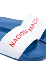 Ojota de hombre con base azul y tira blanca con la inscripción "NAC" en rojo.