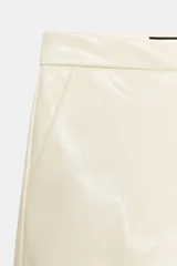 Shorts de tiro bajo confeccionados en material sintético con acabado efecto piel, cuentan con bolsillos delanteros y cierre frontal con cremallera y gancho metálico.
