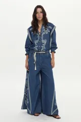 Jean wide leg de denim azul con elástico en la cintura, cordón ajustable y bordados decorativos en los laterales.