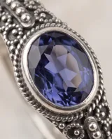 Anillo de plata 925 con diseño calado de estilo étnico y una piedra facetada central de color azul oscuro en corte ovalado.