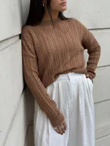 Sweater color crema tejido con diseño en ochos y cuello redondo.