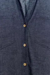 Camisa crop efecto denim color negro, con cuello solapa, escote en V, mangas cortas con trabilla y bolsillos frontales de parche. Cierre frontal con botones.
