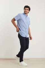 Camisa azul de manga corta, con cuello abotonado y bolsillo en el pecho.