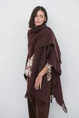 Ruana de tejido de punto en color negro, con diseño de cuello alto y terminaciones con flecos en los bordes.