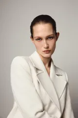 Blazer corto de cuello solapa y manga larga con hombreras. Presenta un diseño cruzado con cierre frontal de dos botones dorados.