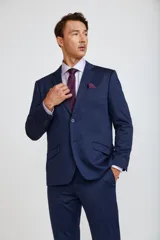Ambo de corte slim compuesto por saco de dos botones y pantalón de vestir a juego, en color azul marino. El saco presenta solapas clásicas, bolsillos laterales con solapa y bolsillo en el pecho con pañuelo decorativo.