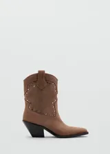 Botines de estilo texano en color marrón claro, confeccionados en piel bovina, con diseño de caña baja, puntera fina y detalles de tachas metálicas en la parte frontal y lateral.