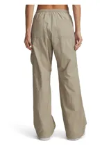 Pantalón cargo Under Armour modelo Unstoppable Woven Utility, color beige, de corte holgado confeccionado en tejido técnico ripstop ultrarresistente con acabado brillante. Cuenta con cintura elástica con bragueta y botón a presión, bolsillos laterales con cremallera, bolsillos traseros abiertos, bolsillo cargo y cordón elástico en los puños para ajustar el bajo.