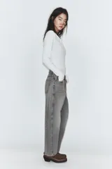 Jeans de tiro medio con diseño cropped, confeccionados en denim gris con efecto lavado. Presentan costuras laterales torcidas, trabillas para cinturón, cinco bolsillos y cierre frontal con cremallera y botón metálico.