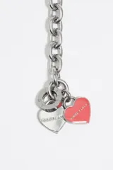 Collar de diseño mixto que combina una sección de perlas irregulares con una sección de cadena de eslabones dorados. Incluye un cierre tipo barra en T y dos dijes colgantes en forma de corazón, uno dorado con logo grabado y otro esmaltado en negro.