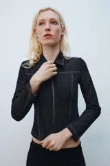 Camisa de denim negra con cuello solapa, manga larga, pespuntes a contraste y cierre frontal con cremallera metálica.