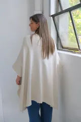 Poncho abierto de tejido de punto color crudo, con mangas tres cuartos y bolsillos frontales aplicados.