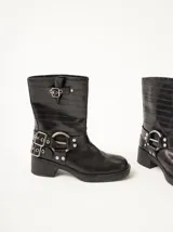 Botas cortas de cuero marrón con textura, hebillas ajustables, apliques circulares y punta cuadrada.