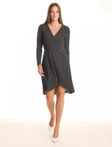 Vestido envolvente de seda fría estampado en blanco y negro, marca Luxology. Presenta escote en V cruzado, cintura elastizada con apliques metálicos en el lateral, manga larga entallada y ruedo asimétrico en el frente.