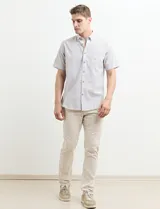 Camisa de manga corta a rayas verticales celestes y blancas, con cuello abotonado y corte clásico.