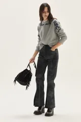 Sweater de tejido de punto color beige con diseño de arabescos en tonos marrones en hombros y mangas. Presenta cuello redondo con cordones decorativos y puños con textura acanalada.