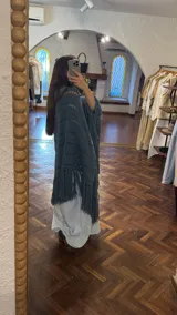 Ruana tejida a mano en lana merino 100%, color verde militar, con diseño de puntos calados y flecos largos en el ruedo.