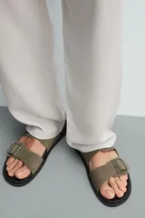 Sandalias de piel con acabado en gamuza, color gris, de diseño plano con plantilla anatómica. Cuenta con dos tiras anchas en el empeine ajustables mediante hebillas metálicas.