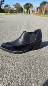 Zapatos de cuero negro con paneles texturizados, punta fina, taco cuadrado y elásticos laterales para mayor comodidad.