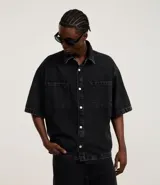 Camisa masculina de jeans negro con lavado marmolado, corte boxy, cuello inglés, manga corta, abotonada al frente y con dos bolsillos de parche en el pecho.
