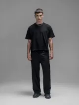 Pantalón cargo negro de corte oversize, confeccionado en microfibra elastizada. Presenta cintura elástica, bolsillos laterales y un bolsillo cargo con cierre de broche a presión. Incluye un sistema de elásticos con tancas en los tobillos para ajustar la apertura.