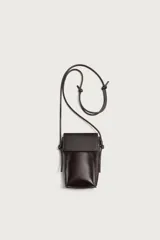 Bandolera porta teléfono de piel marrón con acabado liso, compartimento principal con solapa imantada y asa de hombro ajustable con nudos.