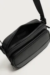 Bandolera de acabado engomado en color negro, con compartimento principal con cierre de cremallera, bolsillo frontal con cremallera y detalle texturizado en la base. Incluye asa de hombro ajustable y extraíble.