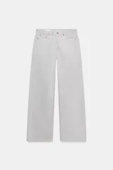 Jeans de tiro medio con diseño de cinco bolsillos y pierna ancha. Presenta un corte recto y holgado con bajo acabado sin costuras y cierre frontal con cremallera y botón metálico.