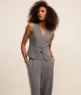 Pantalón de vestir gris de corte recto, con bolsillos laterales y traseros. Se ajusta a la cintura con cierre asimétrico de botones.