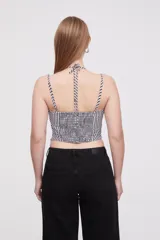 Top corto de escote cuadrado con breteles finos ajustables, confeccionado en tela con estampado de cuadros vichy en blanco y negro. Presenta un pequeño lazo decorativo en el centro del escote y un corte estilo corset con ruedo en punta.