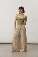 Pantalón marrón claro de corte ancho y fluido, con cintura elástica fruncida y bolsillos laterales.