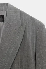 Blazer oversize de corte recto con cuello solapa, manga larga con hombreras y cierre frontal cruzado con botones. Presenta diseño de raya diplomática, bolsillos delanteros y forro interior.