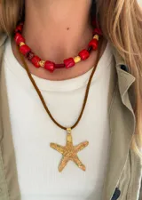 Collar colgante con dije de estrella de mar dorada texturizada, suspendido de un cordón de cuero marrón.