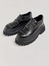 Mocasines color marrón con estampado de cocodrilo y plataforma negra con suela dentada.