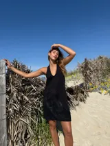 Vestido corto negro con escote halter y apliques de cuero en la falda.