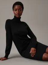 Vestido negro de lana merina, corte recto, largo hasta la rodilla, cuello alto y mangas largas.