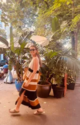 Vestido largo tejido a rayas horizontales en tonos crudo, tostado y negro, con breteles finos y abertura lateral.