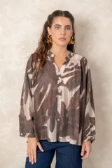 Camisa oversize con estampado abstracto en tonos marrones y beige, cuello mao y cierre frontal con botones. Presenta mangas largas anchas con puños abotonados y un corte holgado.