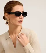 Blusa de punto ajustada color negro, con cuello polo y escote pronunciado en V. Presenta un tejido acanalado vertical en el torso y mangas largas.