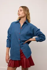 Camisa de jean oversized color azul, con botones rojos y costuras en contraste rojo. Tiene un bolsillo en el pecho.