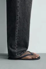 Sandalia de goma color negro, de diseño plano y tiras delgadas en el empeine estilo ojota.
