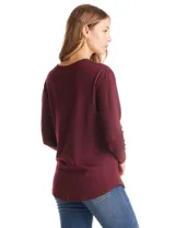 Buzo de tejido fino con escote henley y cierre de botones. Presenta detalles acanalados en hombros, puños y ruedo, con una silueta cómoda y terminación redondeada en la parte inferior.
