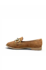 Mocasín de gamuza color beige, con detalle de hebilla metálica dorada en el empeine, costuras visibles y suela plana.