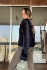 Campera reversible de corte recto y largo a la cadera. Un lado presenta un acabado de napa negra, mientras que el otro lado está confeccionado en piel sintética de color azul noche, extremadamente suave al tacto. Cuenta con mangas largas y un diseño versátil y elegante.