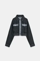 Cazadora de denim negra con cuello solapa, manga larga y bolsillos con solapa en el pecho. Presenta un detalle de tejido a contraste en color denim claro en el delantero y la espalda. Cierre frontal con botones metálicos.