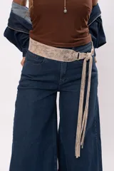 Faja de cuero gamuzado metalizado color visón, con curvatura anatómica, herraje metálico plateado y tiras largas con flecos para atar en nudo.