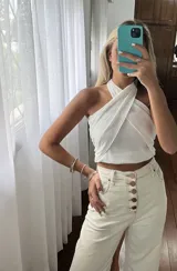 Top negro con diseño cruzado en el frente, estilo halter y con detalles de tachas doradas.