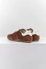 Zapatillas deportivas marrones de gamuza con cordones blancos y detalles en cuero blanco en el talón.