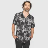 Camisa de manga corta con cuello cubano, confeccionada en viscosa, con estampado de palmeras en contraste sobre fondo negro.