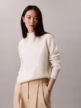Sweater de punto Calvin Klein color blanco marfil, con diseño acanalado, cuello alto y mangas largas de corte raglán.